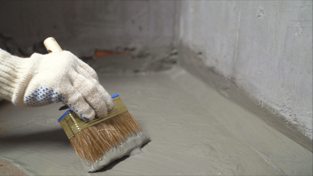 worker applying water insulation to the floor with brush