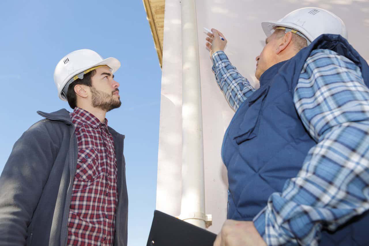 An old man who points somewhere in construction to a younger man