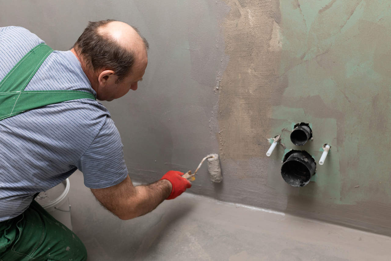 worker applying bathroom wall waterproofing