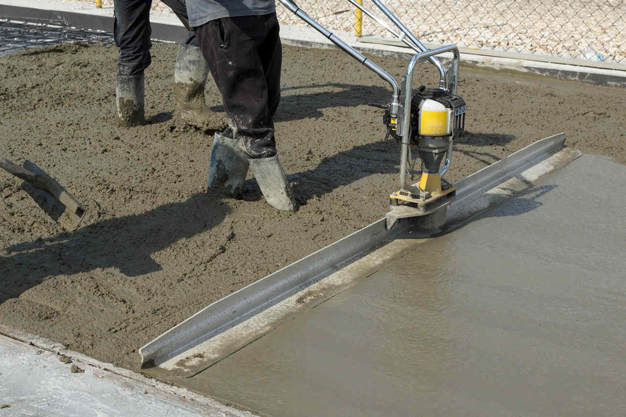 worker leveling the concrete with a machine