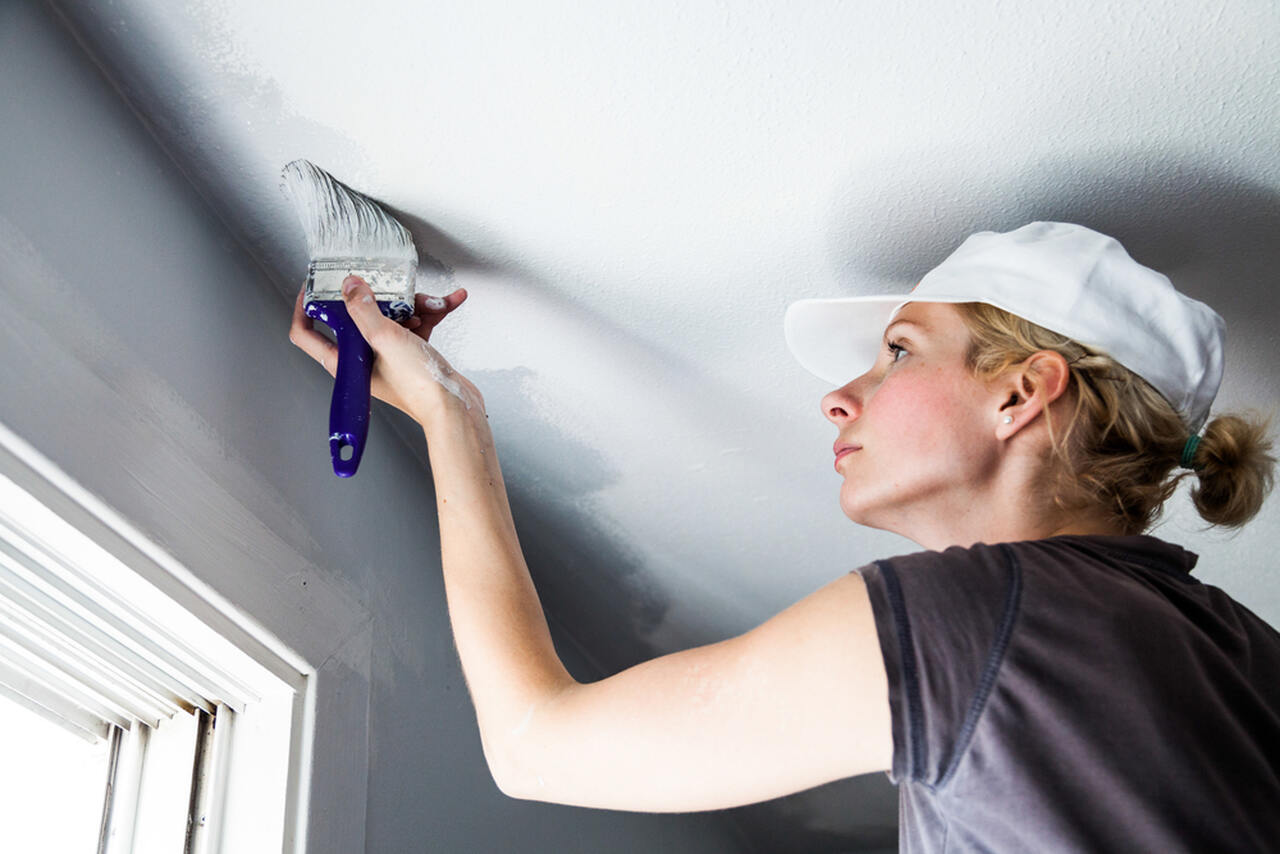 woman worker painting the ceiling