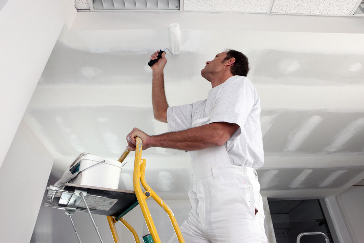 worker applying white ceiling paint