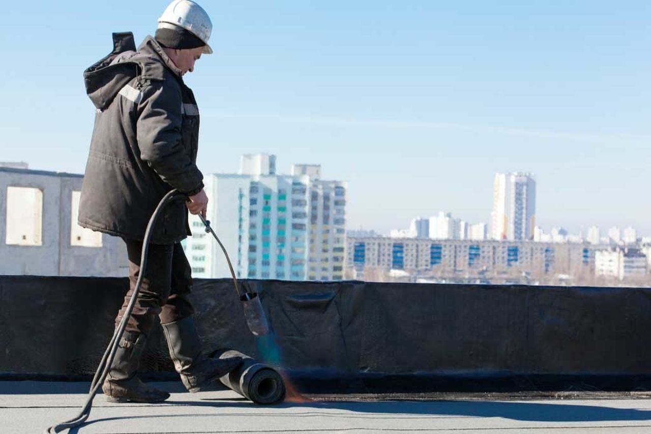 guy appliyng water proofing material onto roof